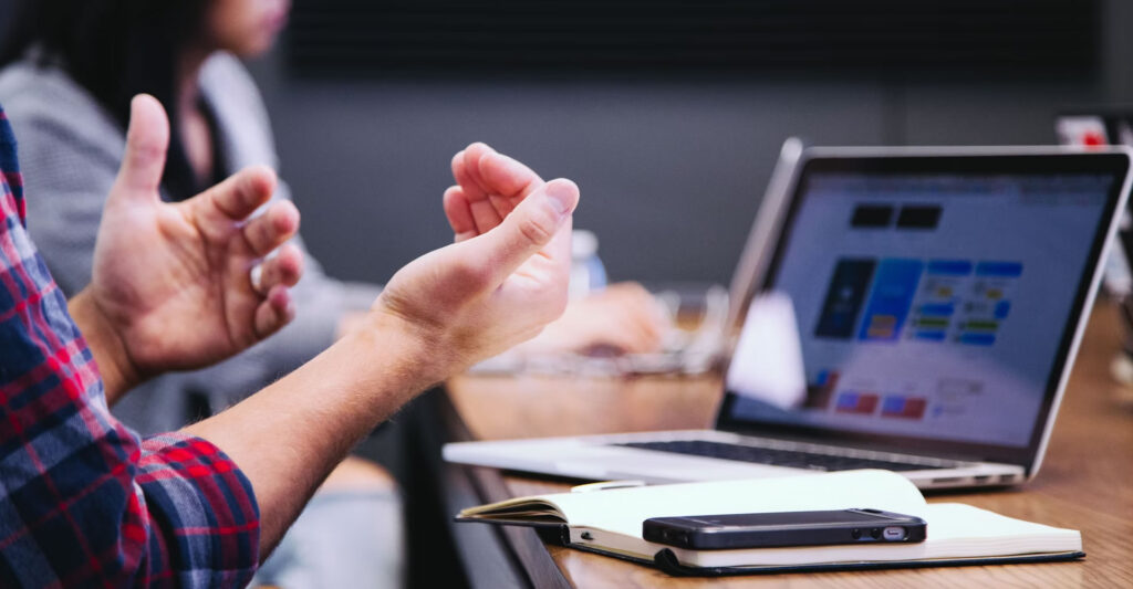 A man sitting at a desk claps his hands, expressing enthusiasm or approval.