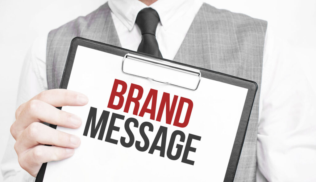 A person in a suit holds a clipboard with the bold text "BRAND MESSAGE." The tone is professional and focused, emphasizing marketing communication.
